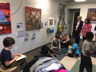 students working on the floor in front of an art exhibit