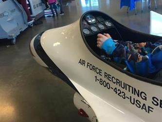 student sitting in an airplane model in a museum