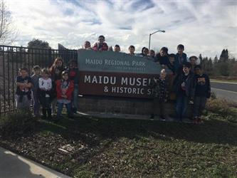 group of students standing in front of the museum sign outside