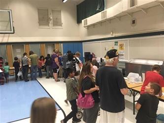 students and parents walking around tables at the science fair