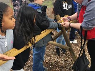 students helping build something out of wood outside