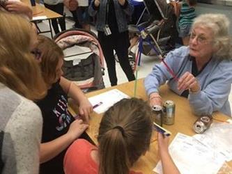 students and parents walking around tables at the science fair