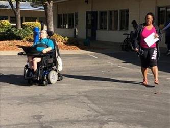 a teacher and a student in a wheelchair outside