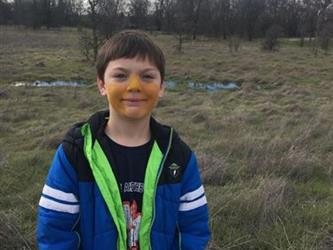 student smiling outside with orange on his face