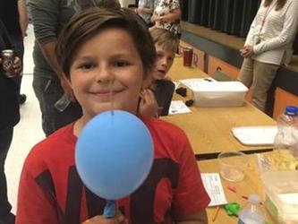 boy showing off his science project at a table in the cafeteria 