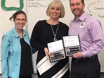 teachers holding awards in a classroom